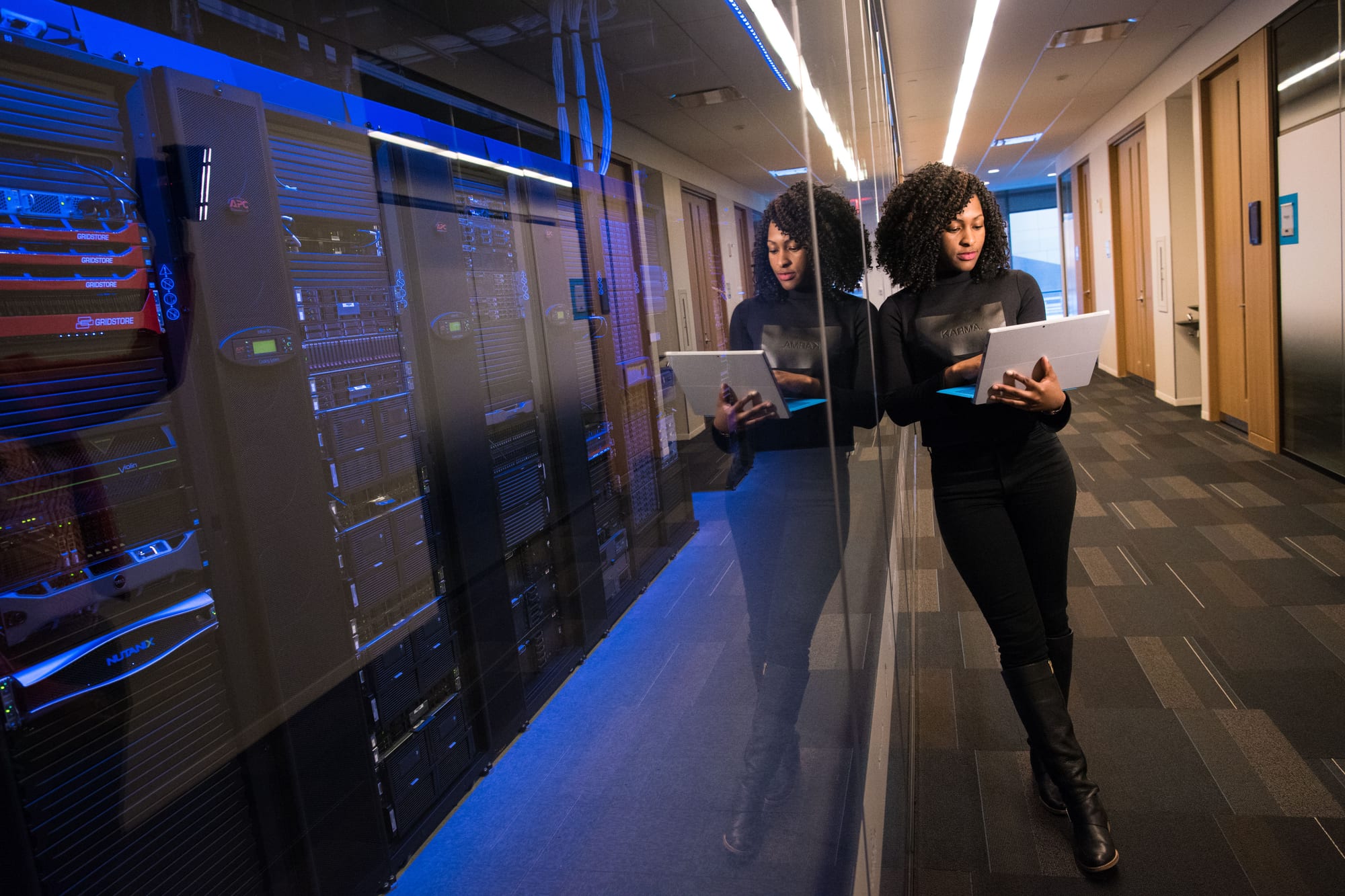 An operator reviewing systems beside a glassed-in server room.